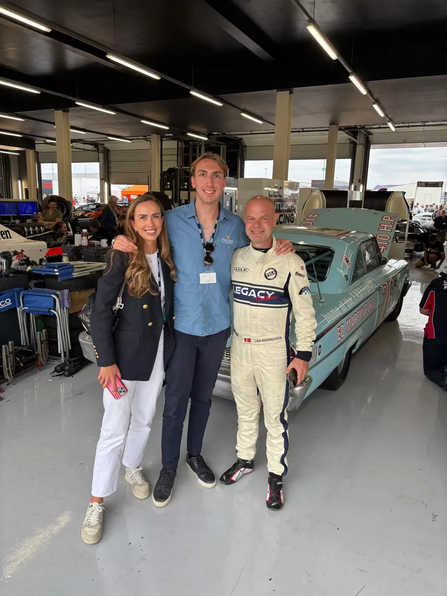 Guests in a race garage beside a classic racing car